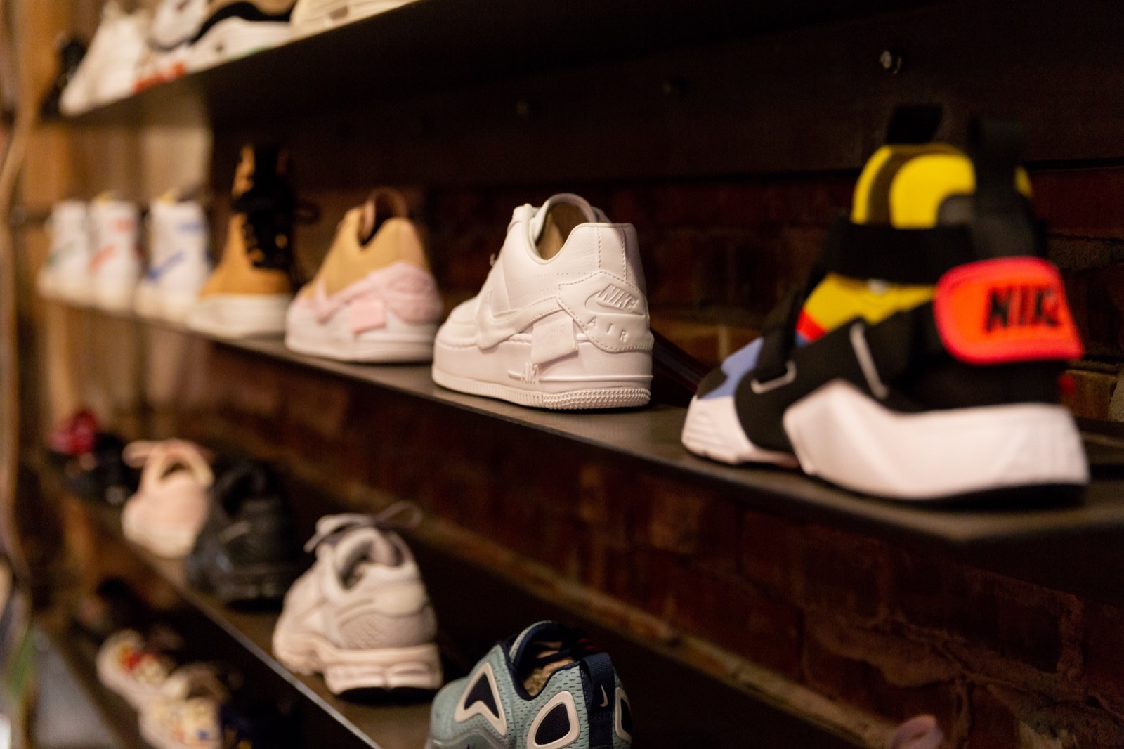 A close view of sneakers displayed on a shelf against an exposed brick wall inside the store.