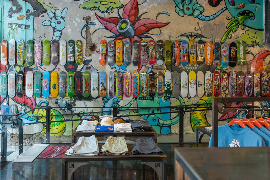 A colorful graffiti-style mural covering the wall behind a full display of skateboard decks.