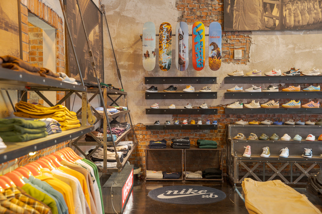 Skateboard decks and a wall of sneakers above a round Nike SB rug and a rack of flannel shirts inside the store.